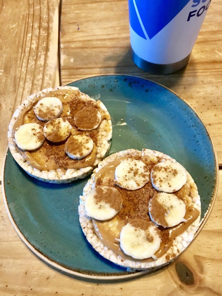 rice cakes with peanut butter, banana, and cinnamon with an iced coffee tumbler